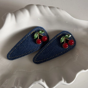 Detail view of denim hair clips with red cherry beads and green crystal leaves