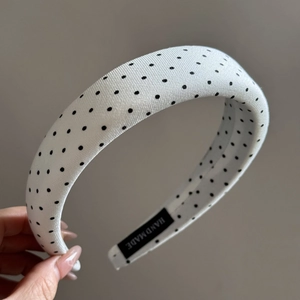 Close-up of white polka dot headband with textured fabric and hand made label detail