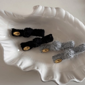 Dettaglio dei fermagli per capelli in maglia con targhette d'oro love in grigio e nero