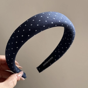 Detailed close-up of handmade navy polka dot padded headband with woven texture label