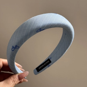 Detailed close-up of light blue twill headband with navy bow pattern and hand made label
