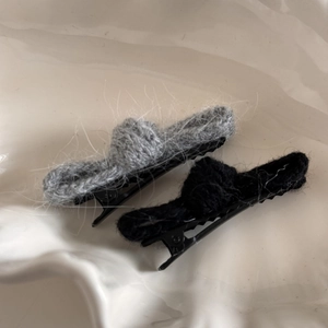 Dettaglio delle mollette per capelli in maglia di mohair grigio e nero con base in metallo