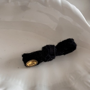 Dettaglio molletta per capelli in maglia nera con targhetta ovale dorata incisa love