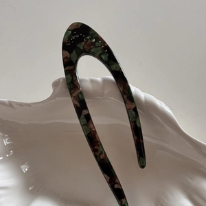 Detail of U-shaped acetate hair pin with dark tortoiseshell pattern and small rhinestones
