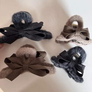 Detail view of plush fabric bow hair claws in charcoal grey and light coffee brown colors