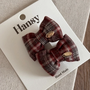 Gros plan sur les barrettes nœuds en tweed à carreaux rouges avec détails dorés