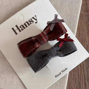 Détail de barrettes à carreaux rouges et nœuds gris sur carte de présentation textile