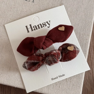 Détail de barrettes nœuds à carreaux rouges et bordeaux avec pendentif cœur doré