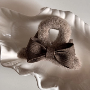 Detailed close-up of dark brown fabric bow and light coffee plush hair claw clip accessory
