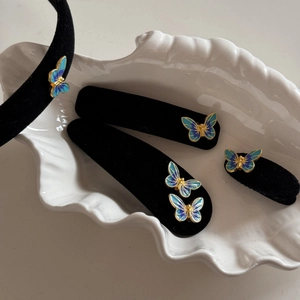 Detail of blue enamel butterflies on black velvet headbands and hair clips in a shell tray
