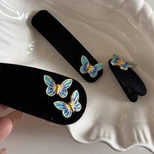 Detail view of blue butterfly hair clips with gold metal edges and velvet texture details