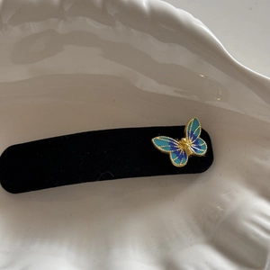 Macro detail of blue butterfly hair clip with gold edges on white textured ceramic base