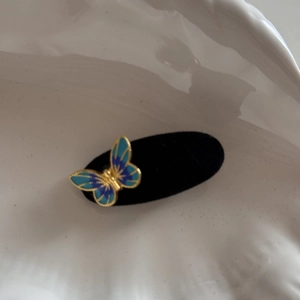 Detail view of a 3D blue butterfly hair clip with velvet texture on a black display pad