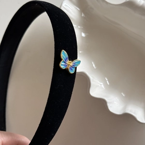 Detail of blue velvet hair clip showing gradient butterfly wings and golden metal trim