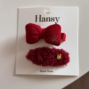 Détail de barrettes festives rouges avec broderie de nœud et strass sur carte de support