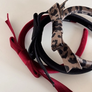 Detail view of handmade bow headbands in red, black, and leopard print velvet fabric