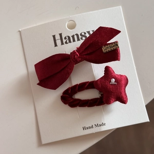 Gros plan d'un nœud en satin bordeaux et d'une pince à cheveux étoile en velours sur carte