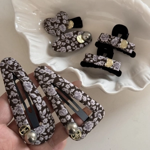 Détail de pinces à cheveux en tissu floral avec boutons dorés et perles élégantes