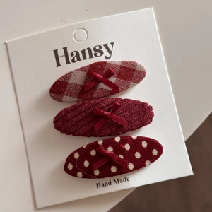 Vue détaillée de trois pinces à cheveux rouges festives aux motifs à carreaux et pois
