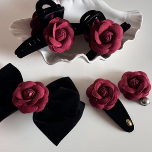 Detailed close-up of dark red fabric rose hair claw set with black velvet texture