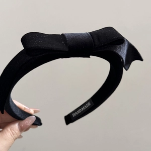 Detail showing the handmade label on a premium black velvet bow headband for women
