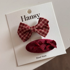 Détail de pinces à cheveux de fête rouges avec nœud écossais et design ovale floqué
