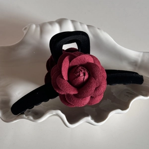 Close-up of a vintage deep red fabric rose on a black matte hair claw clip for women