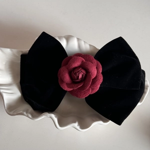 Detail of vintage red fabric rose and black velvet bow hair claw clip in a white shell bowl