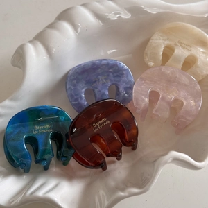 Elegant marble acetate hair claw clips in five colors displayed in a white shell tray