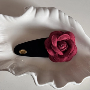 Detail shot of a velvet deep red rose hair claw clip with golden love metal tag