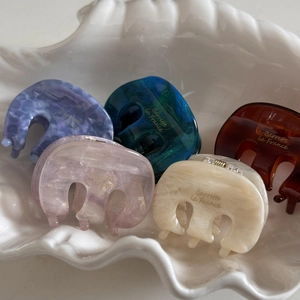 Close-up of five acetate hair claw clips with marble textures in a shell tray