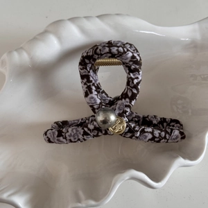 Détail d'une pince à cheveux en tissu fleuri avec perle et pendentif doré