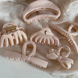 Macro detail of various acrylic hair claws with elegant marble patterns on tulle
