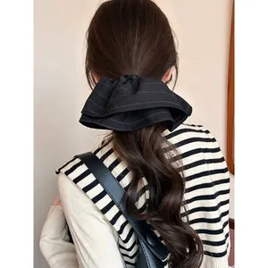Elegant oversized layered black scrunchie with fine white stripes for a retro hair style