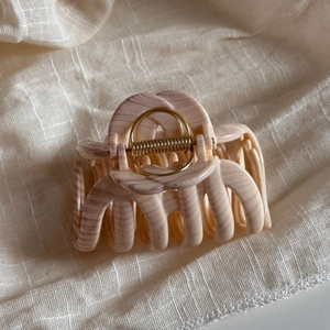 Detail of a large marble texture claw clip with premium gold metal spring on linen fabric