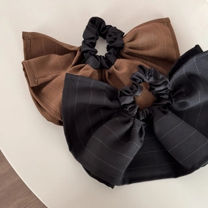 Detail of oversized bow scrunchies in black and brown fabric with fine white stripes