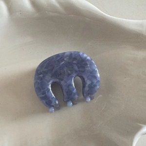 Detail view of small lavender marble acetate hair claw clip on white ceramic tray