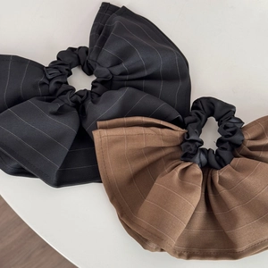 Detailed close-up of large striped scrunchies in black and coffee with elegant pleated fabric