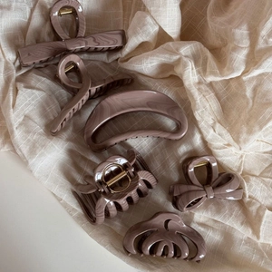 Detail of coffee marble acrylic hair claws with gold springs on beige fabric