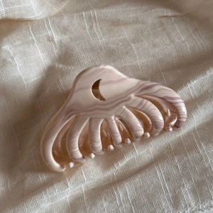 Close-up of pink marble pattern claw clip with unique moon-shaped cutout design