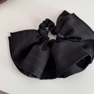 Macro detail of black striped fabric scrunchie with oversized ruffle edge design