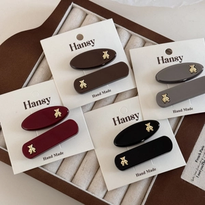 Detailed macro view of hair clips in four colors featuring golden bear metal accents