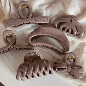 Detail of six various dusty pink marble hair clips on beige linen texture background