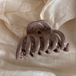Detailed view of dusty rose marble water ripple bow claw clip with golden metal spring