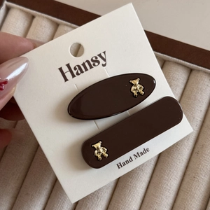 Close-up of brown acrylic hair clips with golden bear accents on a display card