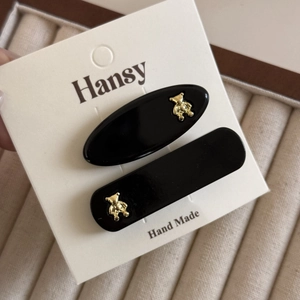 Detail shot of black duckbill hair clips with gold bear accents on display card
