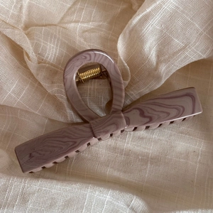 Detail of Morandi purple marble hair claw clip with golden spring on beige fabric