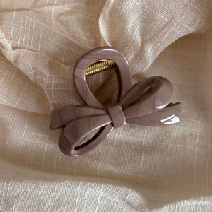 Close-up of marble pattern bow hair claw clip with golden metal spring detail