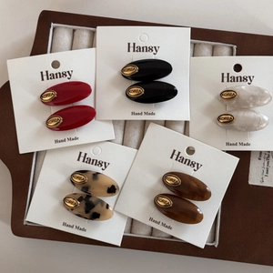 Detailed close-up of colorful acetate oval hair clips with gold Korea emblem labels
