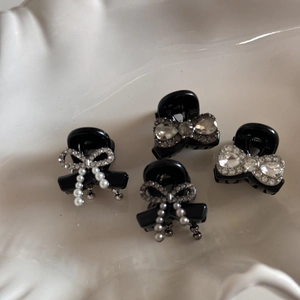 Detail of four mini black hair clips with sparkling rhinestones and white pearls in a ceramic tray